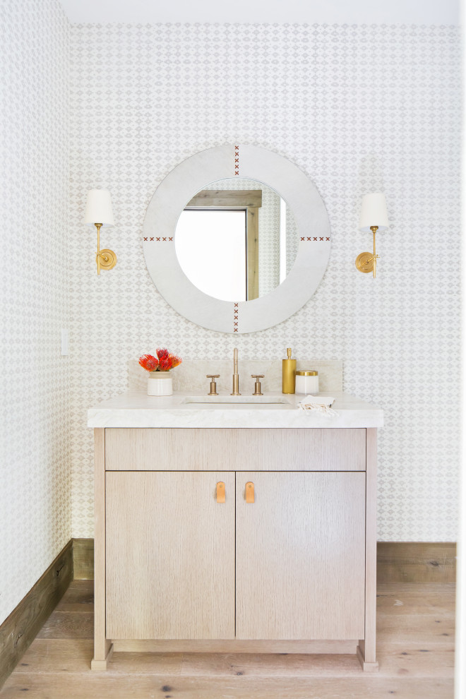Photo of a modern powder room with light hardwood floors, quartzite benchtops, beige benchtops and wallpaper.