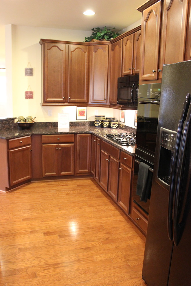 Eat-in kitchen - l-shaped medium tone wood floor eat-in kitchen idea with dark wood cabinets, granite countertops, beige backsplash, black appliances and an island