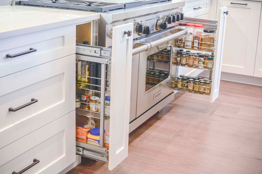 Example of a mid-sized transitional u-shaped medium tone wood floor and brown floor home design design in Calgary with an undermount sink, flat-panel cabinets, white cabinets, marble countertops, gray backsplash, ceramic backsplash, paneled appliances and an island