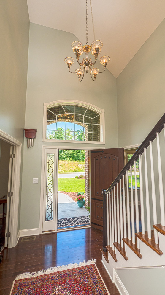 Example of a transitional medium tone wood floor foyer design with blue walls and a dark wood front door