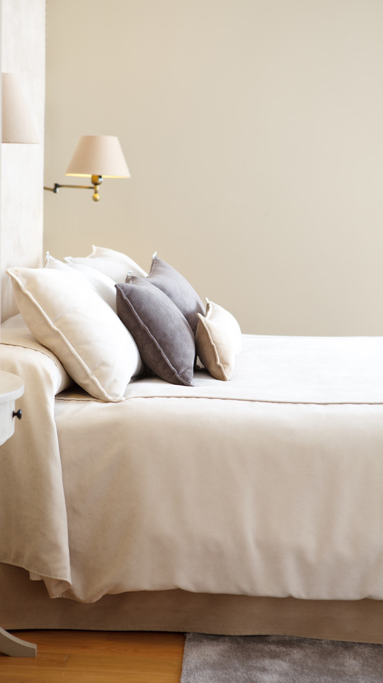 Modelo de dormitorio principal tradicional renovado de tamaño medio con paredes beige, suelo de madera en tonos medios y suelo beige