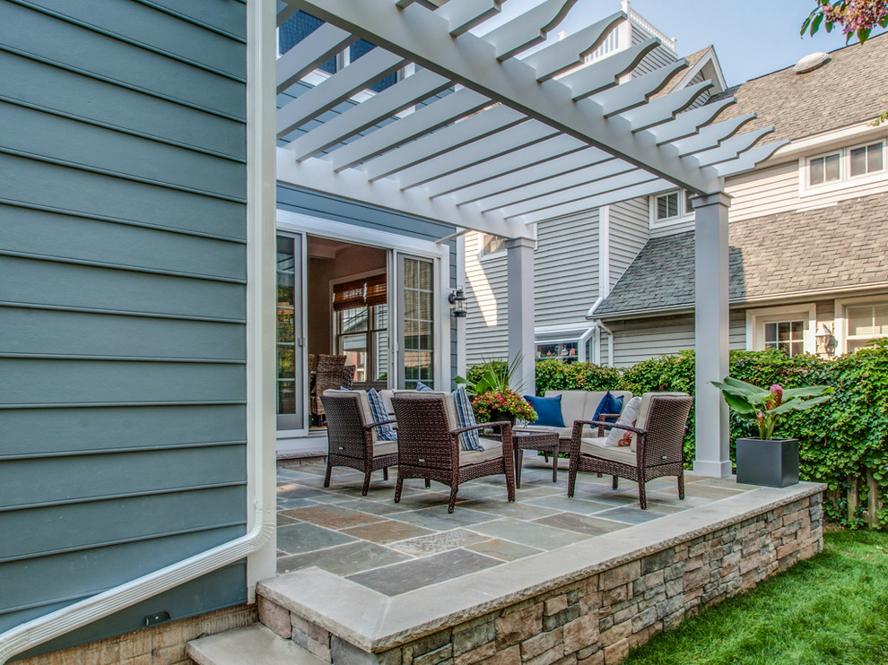 This is an example of a mid-sized beach style backyard patio in Other with tile and a pergola.