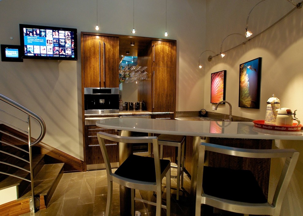 This is an example of a small contemporary l-shaped home bar in Portland with an undermount sink, flat-panel cabinets, medium wood cabinets, glass benchtops, metal splashback and marble floors.
