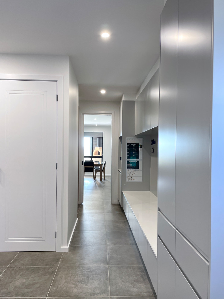 Inspiration for an expansive modern u-shaped dedicated laundry room in Sydney with an undermount sink, flat-panel cabinets, grey cabinets, quartz benchtops, white splashback, ceramic splashback, white walls, ceramic floors, a side-by-side washer and dryer, grey floor and white benchtop.