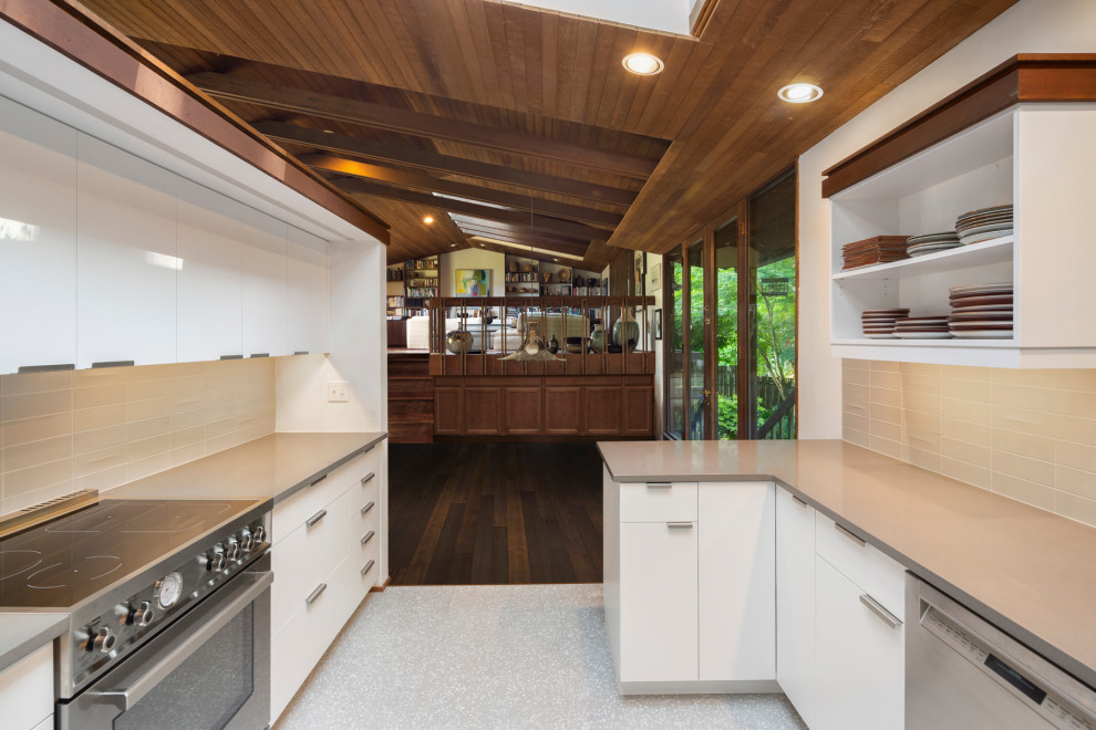 Design ideas for a mid-sized midcentury u-shaped eat-in kitchen in Seattle with a single-bowl sink, flat-panel cabinets, white cabinets, quartz benchtops, grey splashback, ceramic splashback, stainless steel appliances, porcelain floors, no island, grey floor and grey benchtop.