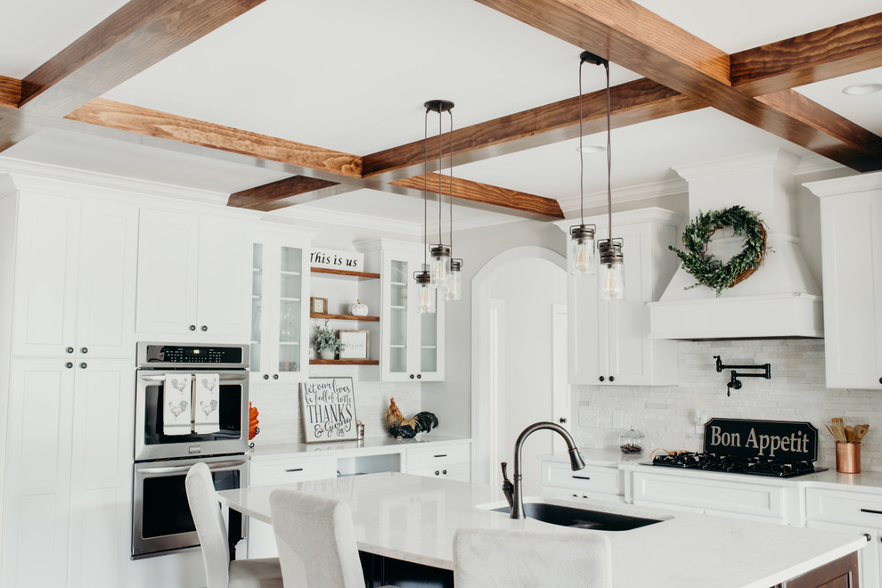 Inspiration for a large country l-shaped eat-in kitchen in Charlotte with an undermount sink, recessed-panel cabinets, white cabinets, quartz benchtops, white splashback, stone tile splashback, stainless steel appliances, medium hardwood floors, with island, brown floor and white benchtop.