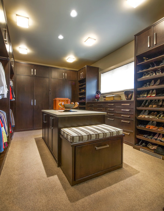 Inspiration for an expansive traditional gender-neutral walk-in wardrobe in Denver with recessed-panel cabinets, dark wood cabinets and carpet.