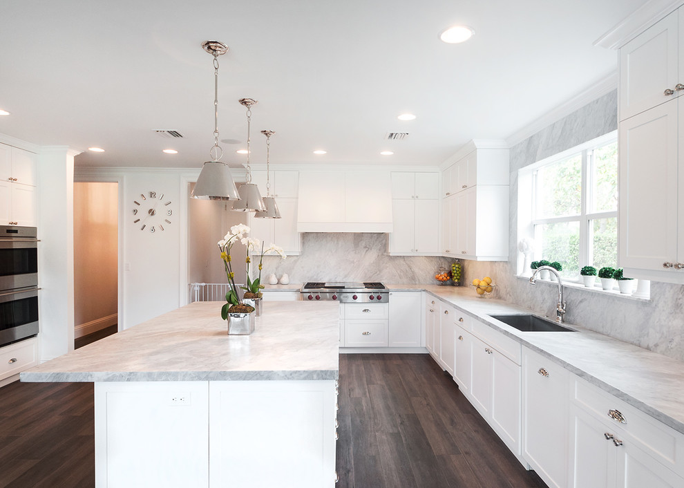 Design ideas for a large transitional u-shaped kitchen in Miami with a drop-in sink, white cabinets, marble benchtops, multi-coloured splashback, stone slab splashback, stainless steel appliances, porcelain floors, with island, shaker cabinets, brown floor and grey benchtop.