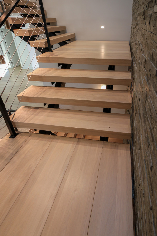 Источник вдохновения для домашнего уюта: большая лестница на больцах в стиле фьюжн с деревянными ступенями, металлическими перилами и кирпичными стенами