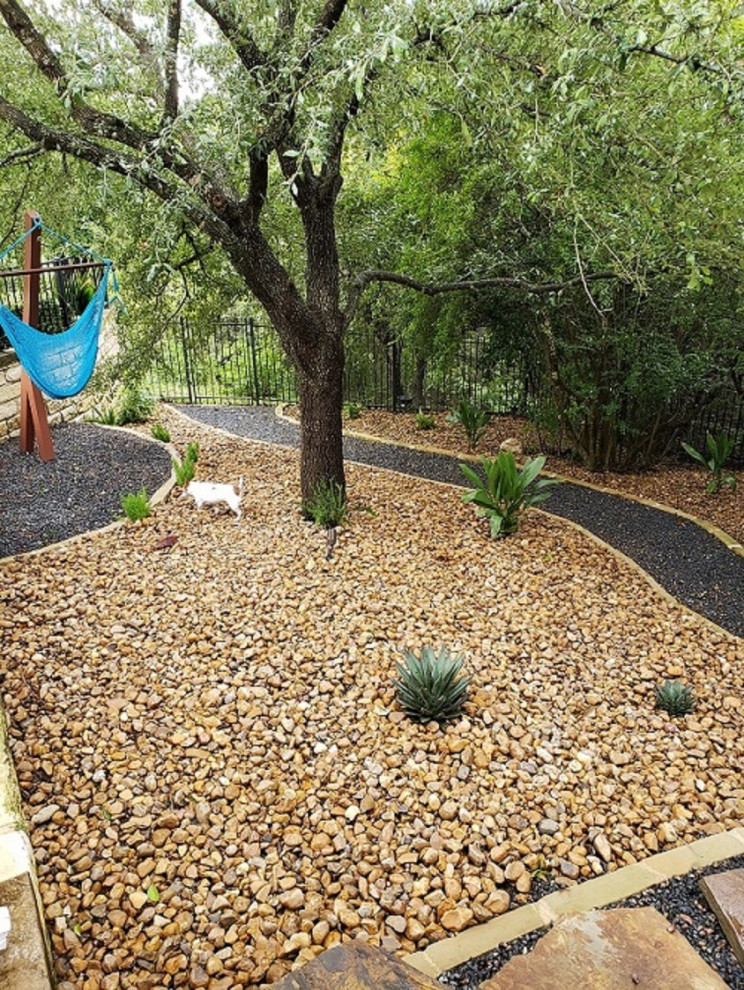 Photo of a large contemporary backyard full sun xeriscape in Austin with with path and river rock.