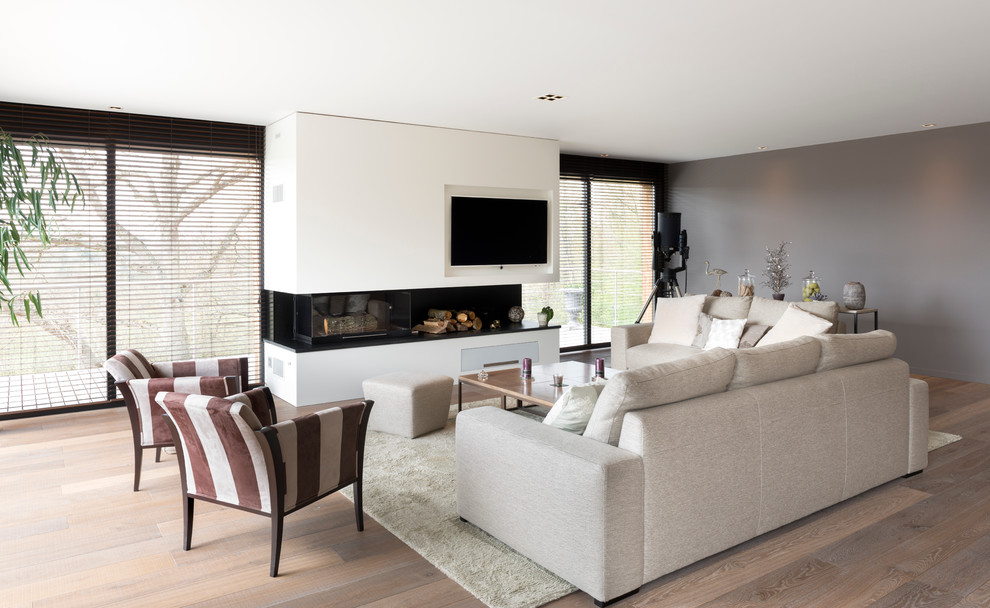 Photo of a mid-sized contemporary formal open concept living room in Le Havre with grey walls, medium hardwood floors, a ribbon fireplace and a wall-mounted tv.