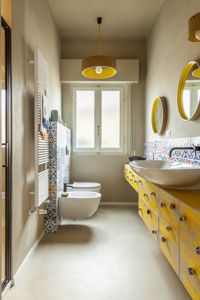 Идея дизайна: ванная комната среднего размера в средиземноморском стиле с плоскими фасадами, желтыми фасадами, инсталляцией, разноцветной плиткой, керамической плиткой, разноцветными стенами, бетонным полом, душевой кабиной, настольной раковиной, столешницей из дерева, душем с распашными дверями, желтой столешницей, тумбой под одну раковину и встроенной тумбой