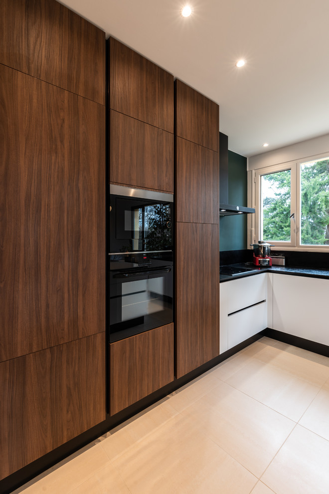 Mid-sized transitional l-shaped open plan kitchen in Lyon with an undermount sink, solid surface benchtops, black splashback, stainless steel appliances, ceramic floors, with island, beige floor and black benchtop.