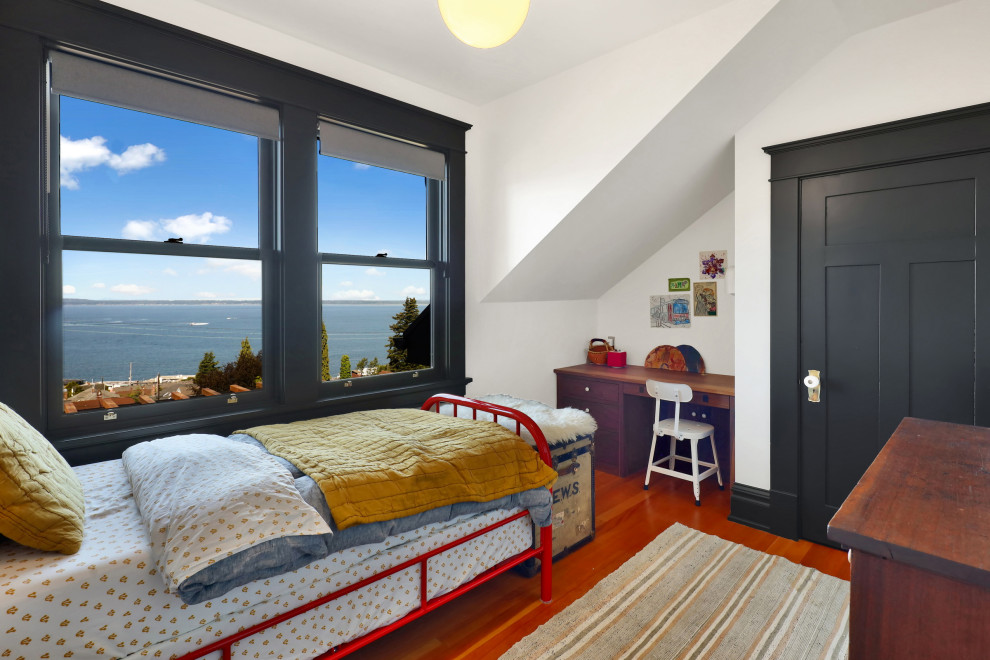 Photo of a small arts and crafts gender-neutral kids' bedroom for kids 4-10 years old in Seattle with white walls, light hardwood floors, orange floor and vaulted.