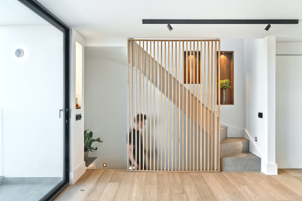 Свежая идея для дизайна: изогнутая лестница в современном стиле с ступенями из известняка, подступенками из известняка и деревянными перилами - отличное фото интерьера