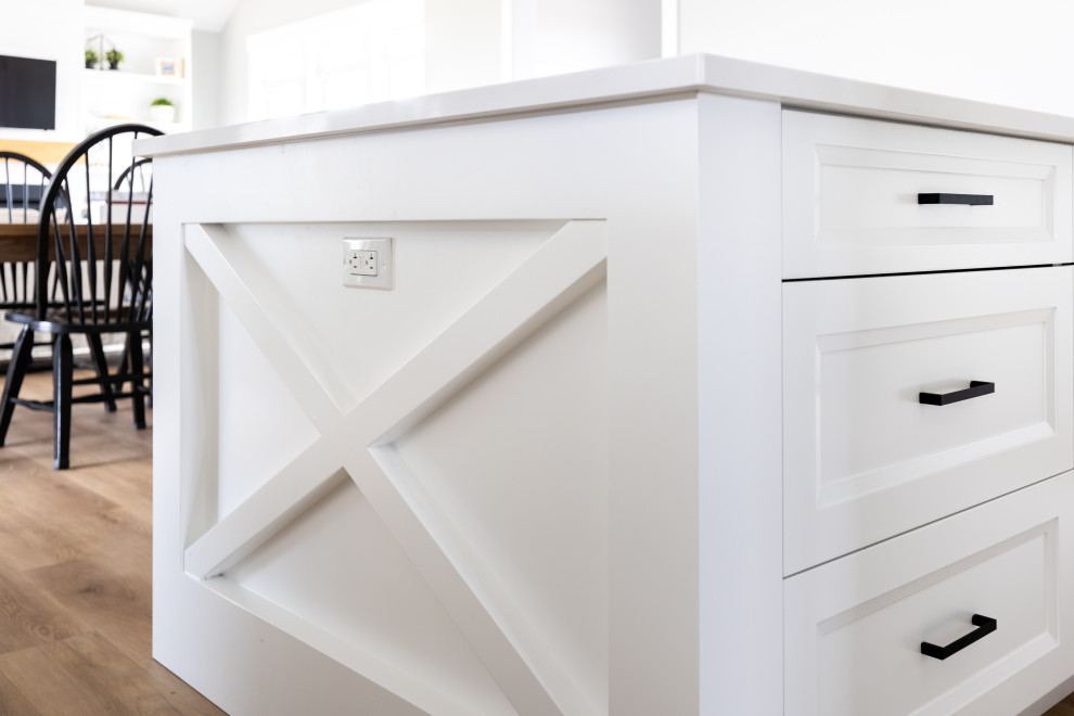 Klassisk inredning av ett mellanstort vit vitt kök, med en undermonterad diskho, skåp i shakerstil, vita skåp, bänkskiva i kvarts, rostfria vitvaror, mellanmörkt trägolv, en köksö och flerfärgat golv
