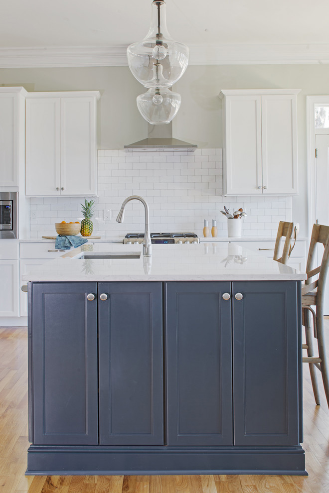 Inspiration for a large transitional l-shaped open plan kitchen in Other with an undermount sink, shaker cabinets, blue cabinets, quartz benchtops, white splashback, subway tile splashback, stainless steel appliances, medium hardwood floors, with island, brown floor and white benchtop.