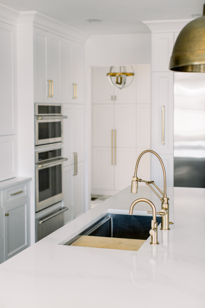 Mid-sized transitional single-wall dark wood floor, brown floor and exposed beam eat-in kitchen photo with an undermount sink, shaker cabinets, white cabinets, quartz countertops, white backsplash, subway tile backsplash, stainless steel appliances, an island and white countertops