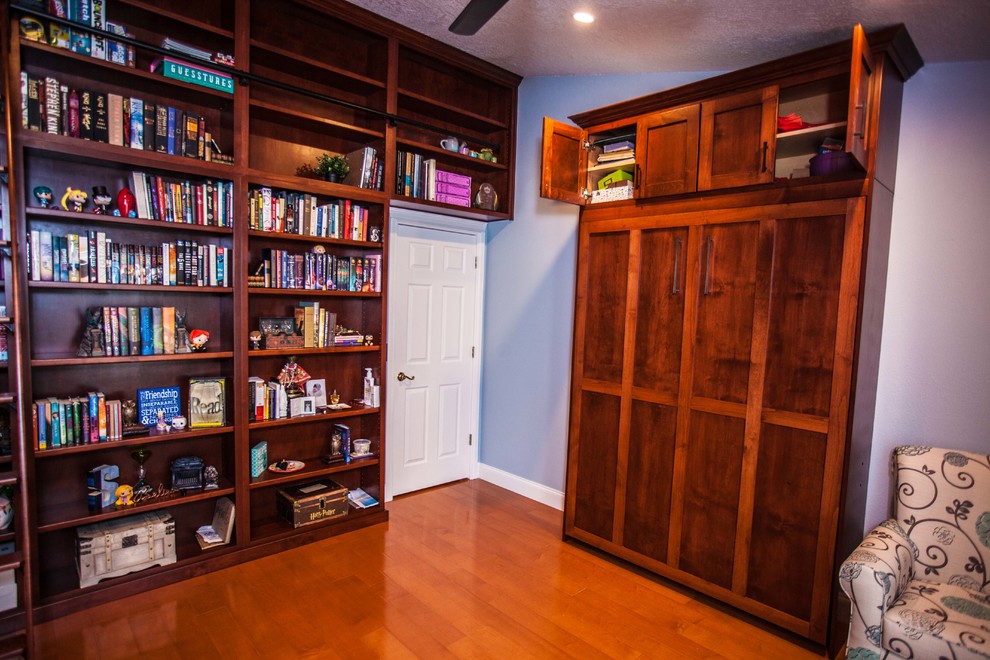 Design ideas for a mid-sized traditional home office in Orlando with a library, blue walls, medium hardwood floors, no fireplace, a built-in desk and brown floor.