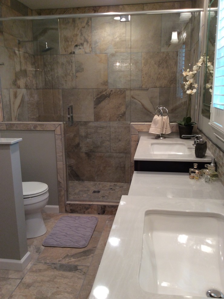 Mid-sized transitional master beige tile and ceramic tile ceramic tile freestanding bathtub photo in Birmingham with an undermount sink, flat-panel cabinets, dark wood cabinets, marble countertops, a two-piece toilet and beige walls