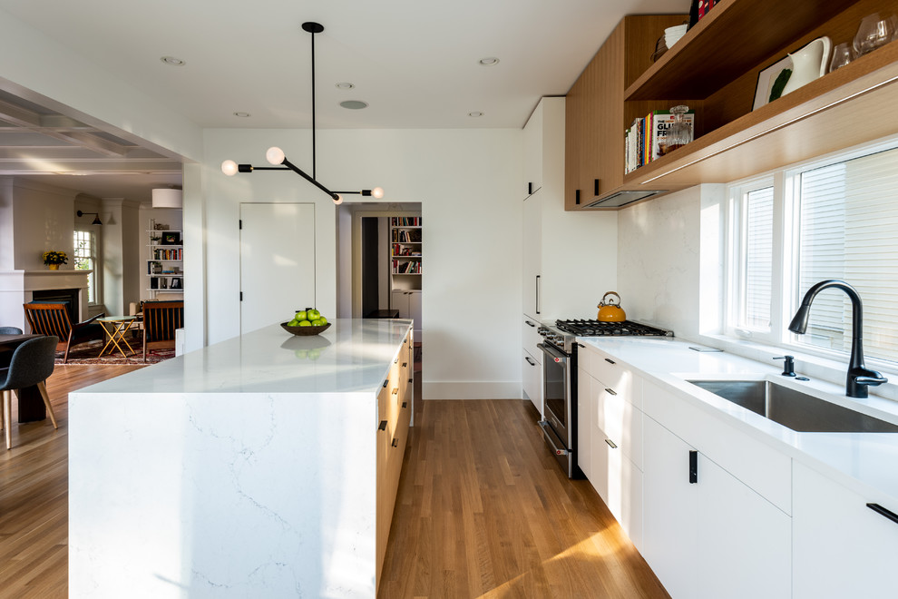 Inspiration for a mid-sized contemporary galley separate kitchen in Seattle with an undermount sink, flat-panel cabinets, white cabinets, quartz benchtops, white splashback, marble splashback, panelled appliances, medium hardwood floors, with island and white benchtop.