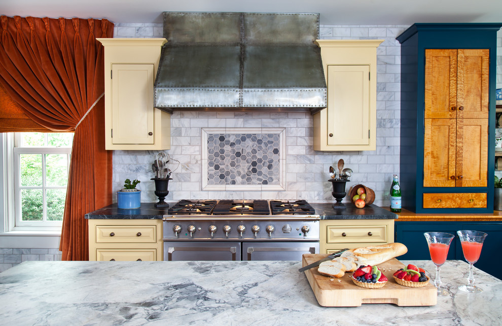 Eat-in kitchen - mid-sized farmhouse l-shaped medium tone wood floor eat-in kitchen idea in Philadelphia with a farmhouse sink, shaker cabinets, yellow cabinets, marble countertops, white backsplash, subway tile backsplash, stainless steel appliances and an island