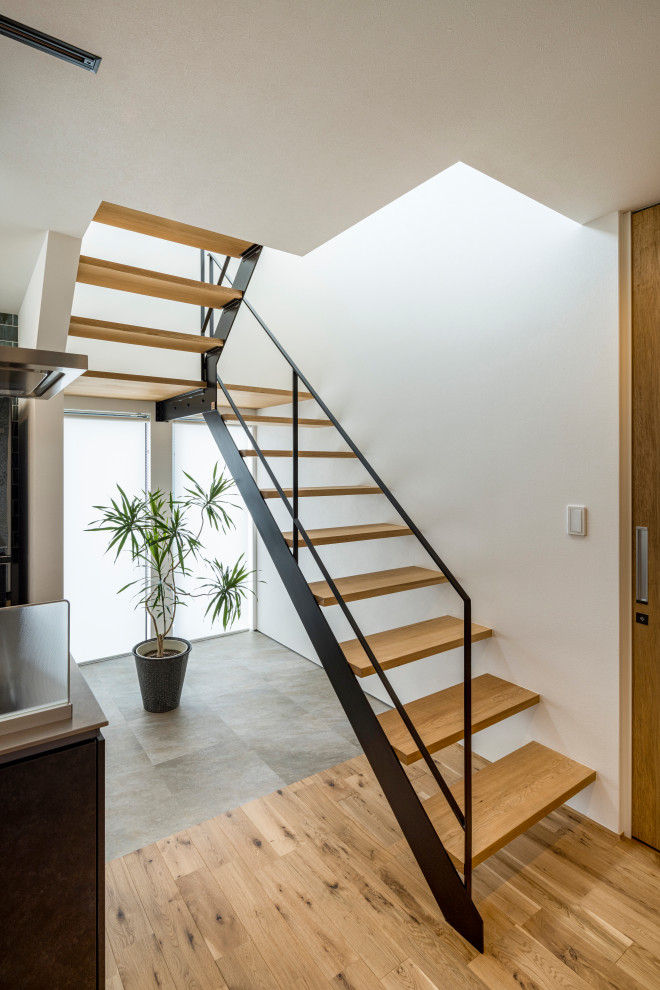 Cette photo montre un escalier sans contremarche tendance en U avec des marches en bois et un garde-corps en métal.
