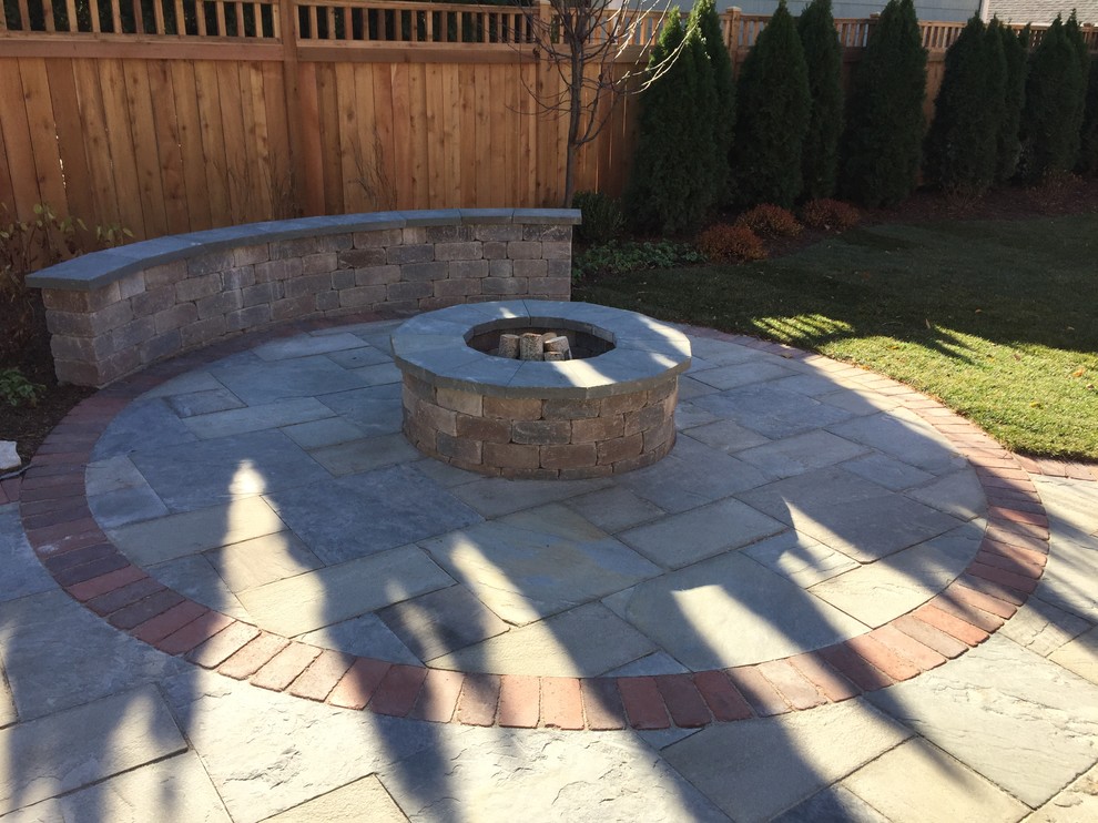 This is an example of a mid-sized contemporary backyard patio in Chicago with a fire feature, natural stone pavers and a pergola.