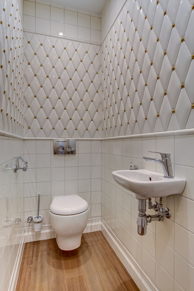 This is an example of a contemporary powder room in Orlando with a wall-mount toilet, white tile, a wall-mount sink and brown floor.