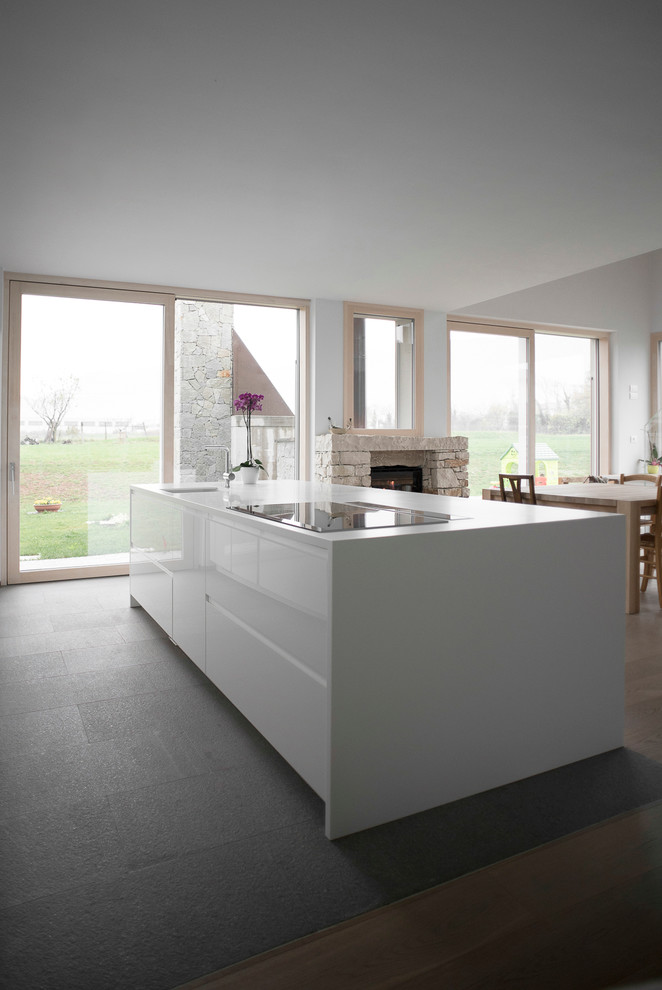 This is an example of an expansive contemporary open plan kitchen in Venice with flat-panel cabinets, white cabinets, slate floors and with island.
