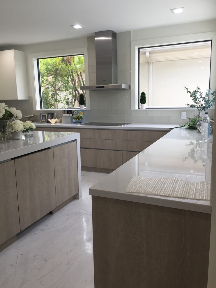Photo of a large contemporary u-shaped open plan kitchen in Miami with an undermount sink, flat-panel cabinets, light wood cabinets, quartz benchtops, white splashback, glass tile splashback, stainless steel appliances, marble floors, with island and white floor.