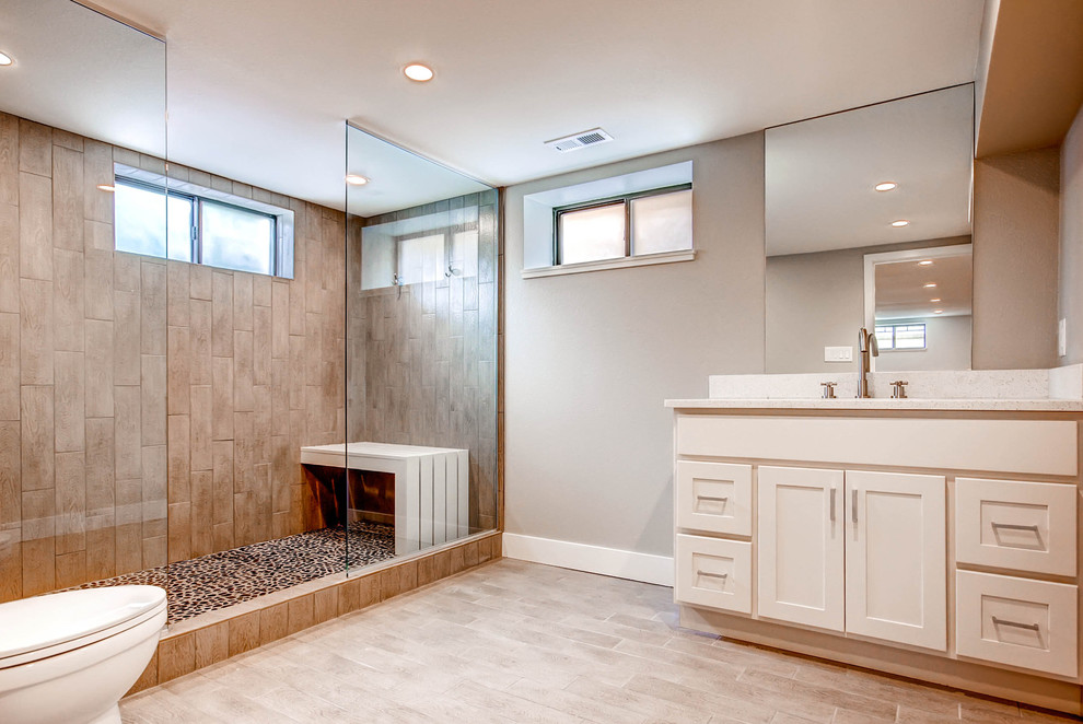 Large transitional 3/4 brown tile and porcelain tile pebble tile floor doorless shower photo in Denver with an undermount sink, shaker cabinets, white cabinets, quartz countertops, a one-piece toilet and beige walls