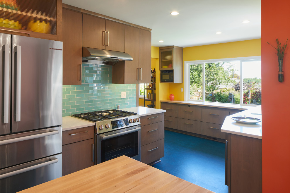 Bild på ett mellanstort 50 tals vit vitt kök, med en undermonterad diskho, släta luckor, skåp i mellenmörkt trä, bänkskiva i kvartsit, flerfärgad stänkskydd, stänkskydd i glaskakel, rostfria vitvaror, linoleumgolv, en köksö och blått golv