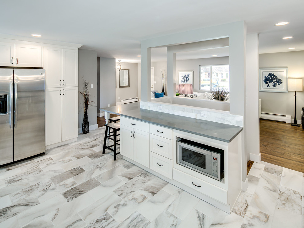 This is an example of a large transitional u-shaped eat-in kitchen in Denver with a single-bowl sink, shaker cabinets, white cabinets, quartzite benchtops, grey splashback, stainless steel appliances, porcelain floors and no island.