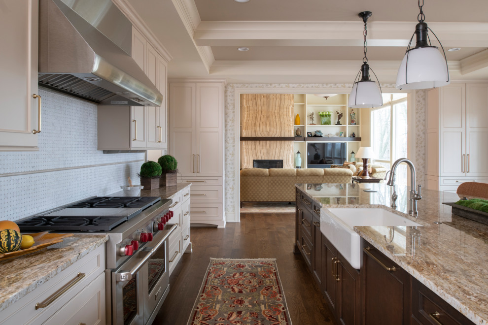 Photo of a large traditional l-shaped separate kitchen in Minneapolis with a farmhouse sink, recessed-panel cabinets, white cabinets, granite benchtops, white splashback, ceramic splashback, stainless steel appliances, dark hardwood floors, with island, brown floor, multi-coloured benchtop and recessed.
