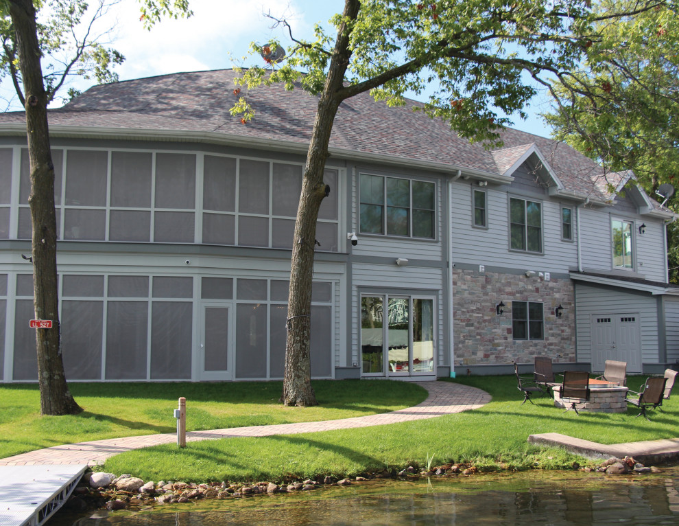 Photo of a large transitional two-storey grey house exterior in Milwaukee with a gable roof and a shingle roof.
