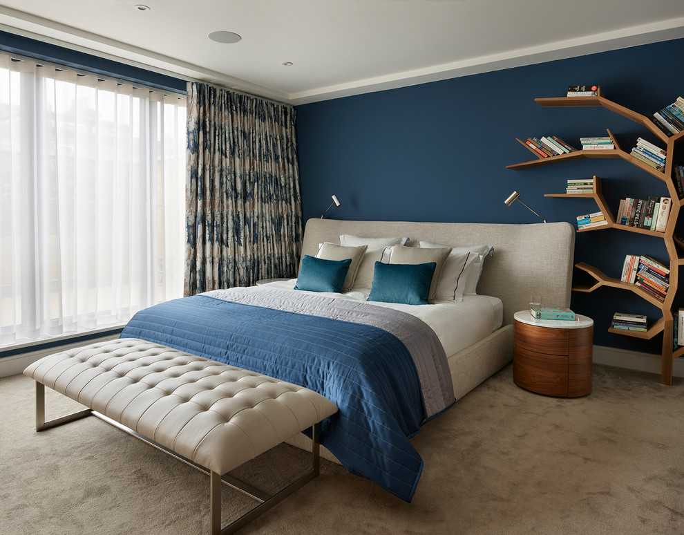 This is an example of a contemporary master bedroom in London with blue walls, carpet and beige floor.