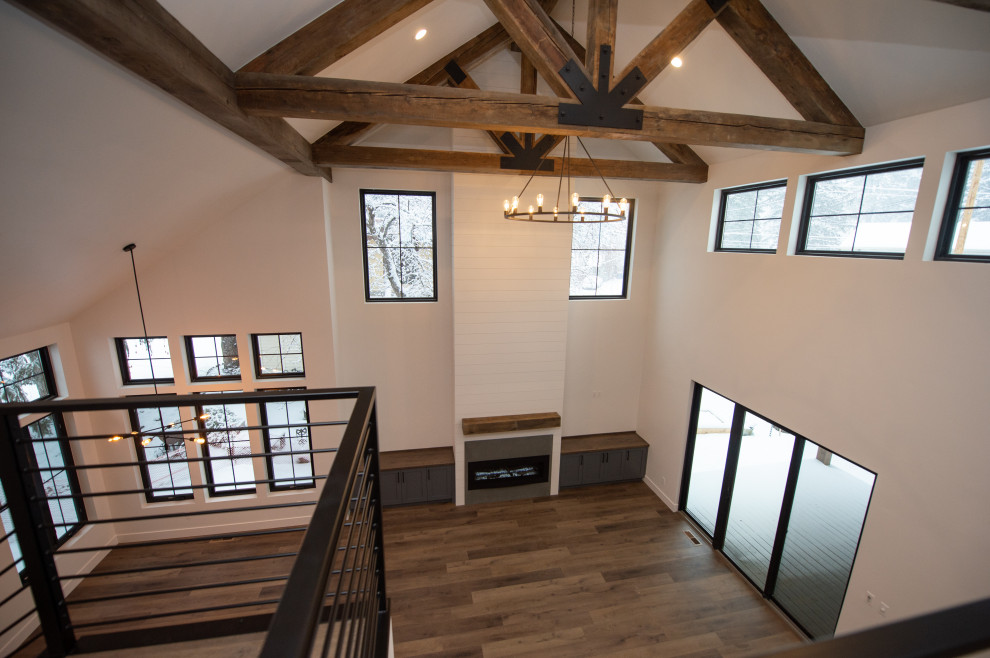 Diseño de salón abierto de estilo de casa de campo de tamaño medio con marco de chimenea de hormigón, suelo marrón, vigas vistas y machihembrado