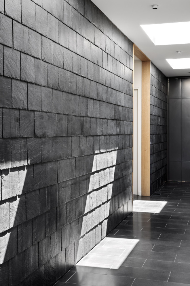На фото: коридор среднего размера в современном стиле с черными стенами, панелями на части стены и черным полом