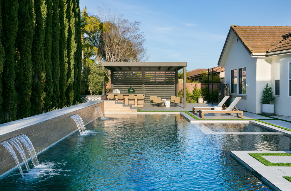 Cette image montre un grand piscine avec aménagement paysager arrière traditionnel rectangle avec du carrelage.