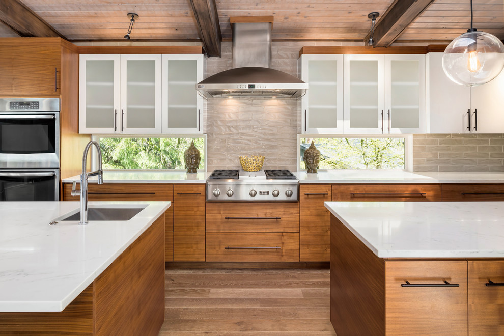 Inspiration for a large midcentury l-shaped open plan kitchen in Portland with an undermount sink, flat-panel cabinets, light wood cabinets, quartzite benchtops, stainless steel appliances, light hardwood floors, beige floor, multiple islands and beige splashback.