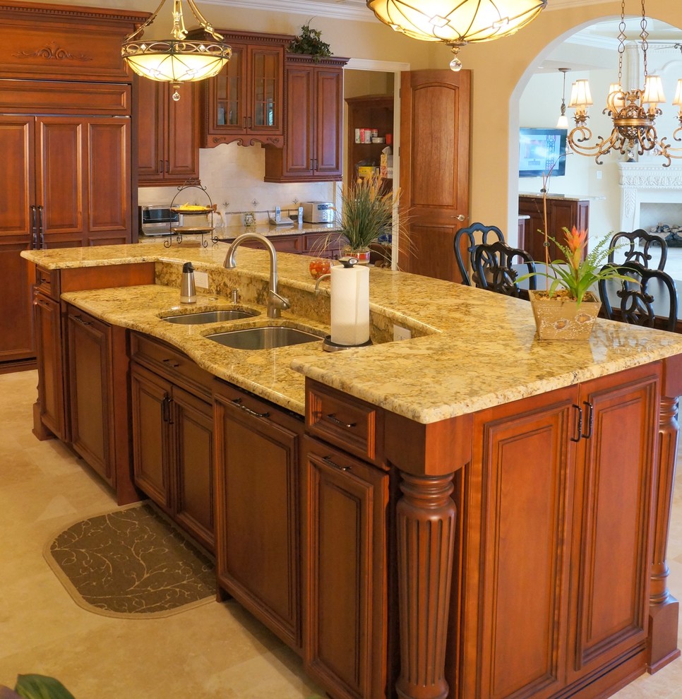 Inspiration for a large traditional eat-in kitchen in Tampa with a double-bowl sink, raised-panel cabinets, orange cabinets, granite benchtops, beige splashback, mosaic tile splashback, panelled appliances, travertine floors, with island and beige floor.