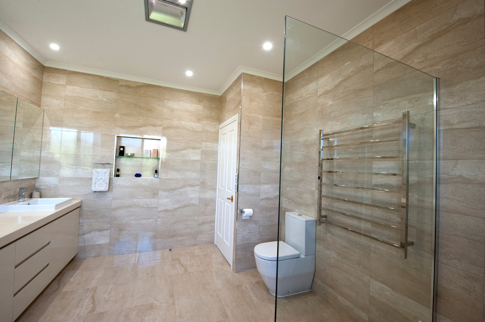 Design ideas for a large contemporary master bathroom in Melbourne with beige cabinets, a freestanding tub, an open shower, a two-piece toilet, black tile, glass sheet wall, beige walls, ceramic floors, an integrated sink and engineered quartz benchtops.