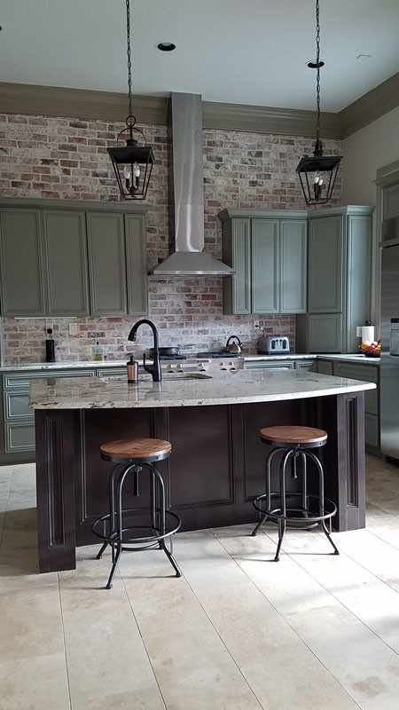 Photo of a mid-sized industrial l-shaped eat-in kitchen in Houston with an undermount sink, recessed-panel cabinets, green cabinets, granite benchtops, red splashback, brick splashback, stainless steel appliances, ceramic floors, with island and beige floor.