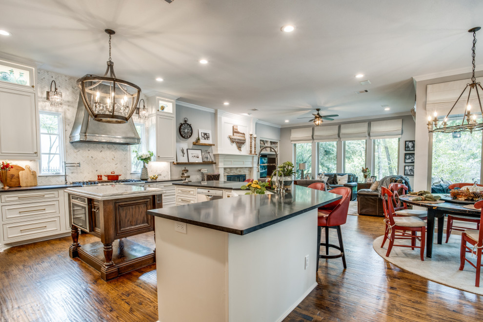 Photo of a mid-sized traditional u-shaped eat-in kitchen in Dallas with a farmhouse sink, beaded inset cabinets, white cabinets, granite benchtops, white splashback, marble splashback, stainless steel appliances, medium hardwood floors, with island and black benchtop.