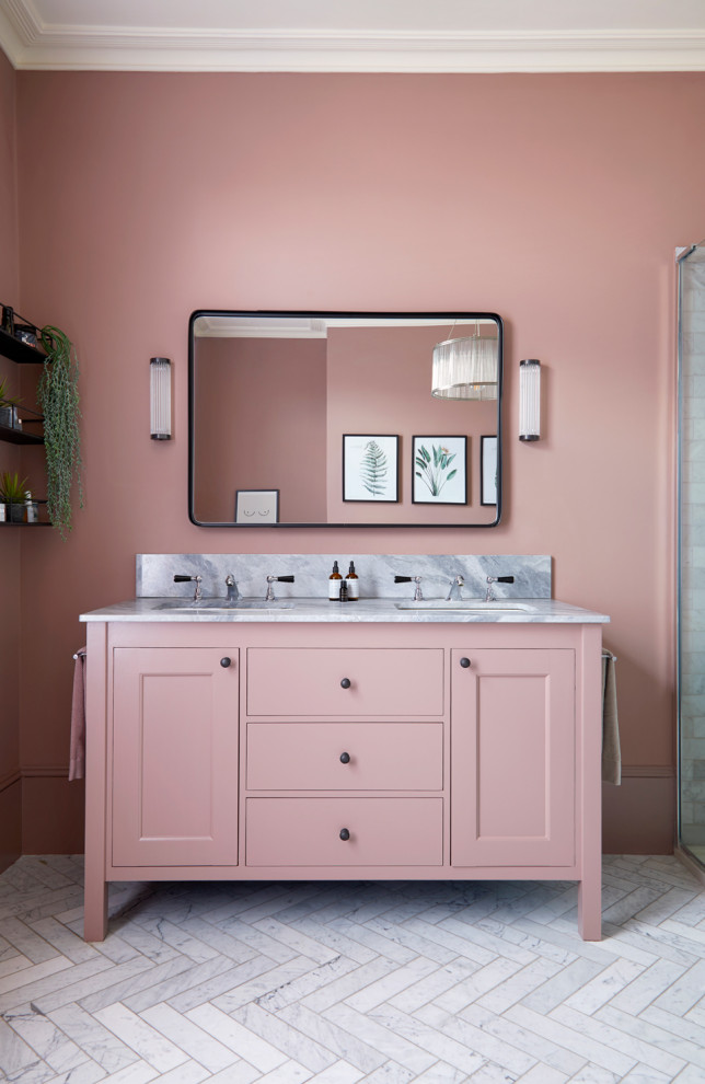 Пример оригинального дизайна: большая главная ванная комната в современном стиле с розовыми стенами, мраморной столешницей, тумбой под две раковины, фасадами с утопленной филенкой, отдельно стоящей ванной, открытым душем, раздельным унитазом, полом из керамогранита, врезной раковиной, серым полом, душем с распашными дверями, серой столешницей и напольной тумбой