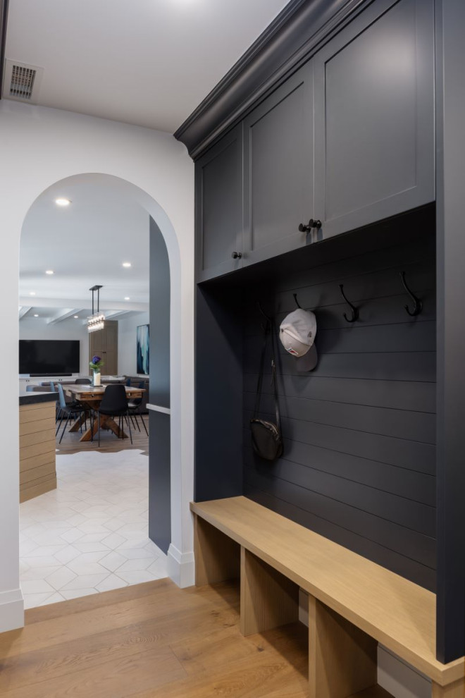 Mid-sized transitional medium tone wood floor and brown floor mudroom photo in Vancouver with white walls