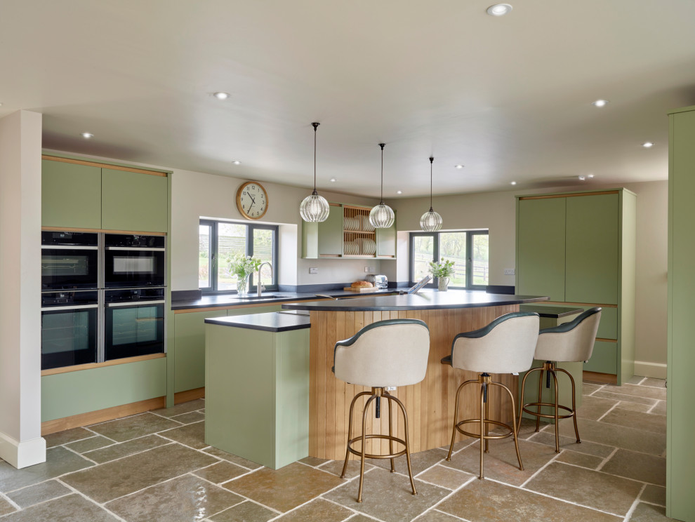 Design ideas for a large contemporary l-shaped kitchen in Gloucestershire with flat-panel cabinets, granite worktops, black appliances, an island, black worktops, a single-bowl sink, green cabinets and brown floors.