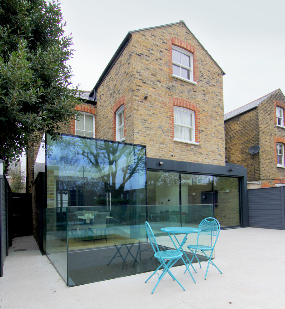 Photo of a large contemporary three-storey glass brown duplex exterior in London with a gable roof and a tile roof.