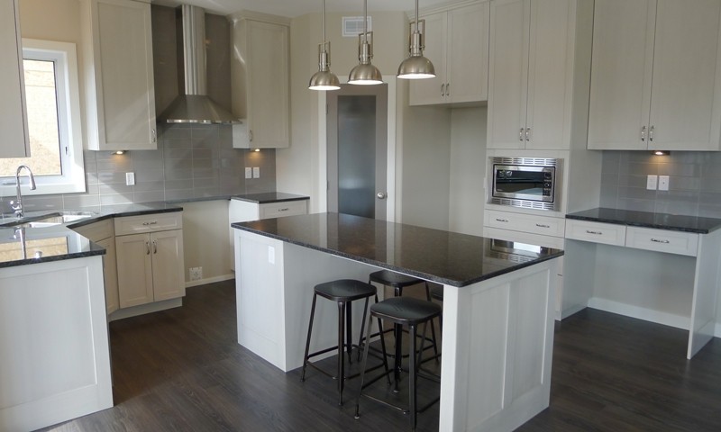 Small transitional l-shaped dark wood floor eat-in kitchen photo with an undermount sink, shaker cabinets, white cabinets, granite countertops, gray backsplash, ceramic backsplash, stainless steel appliances and an island